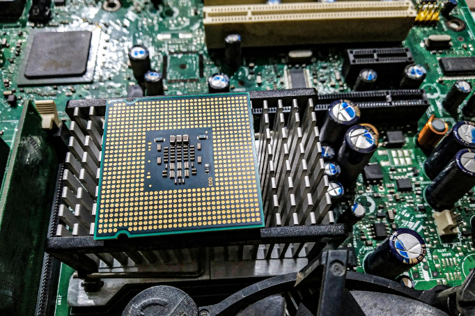 Computer processor (CPU) resting on a heatsink, showing motherboard circuitry, capacitors, and electronic components.